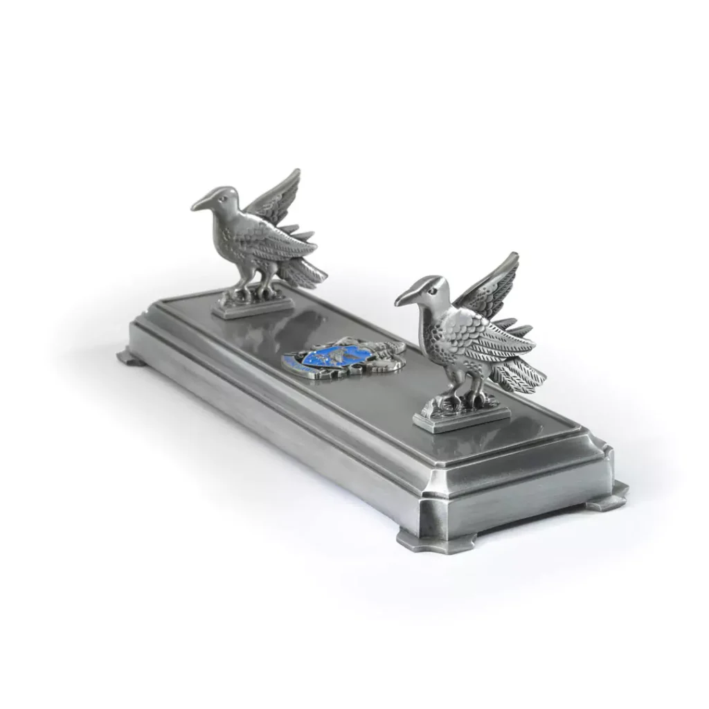 Detaillierter, offiziell lizenzierter Harry Potter Zauberstabständer im Ravenclaw-Design. Der Metallständer zeigt den Adler und das Ravenclaw-Wappen und hält einen Zauberstab auf einem dunklen Holztisch. Ein authentisches Sammlerstück für Fans, erhältlich in unserem Kostümladen – deinem lokalen Harry Potter Shop in Berlin.