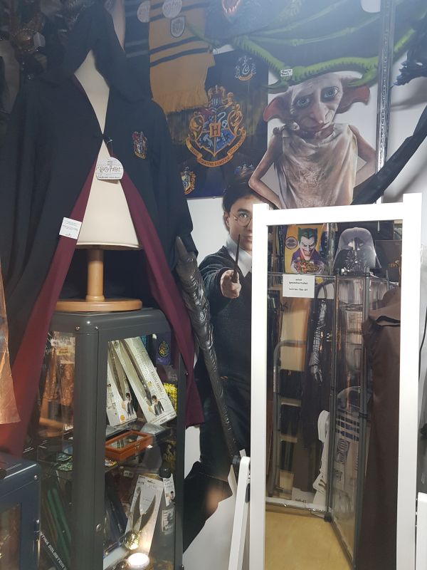 Präsentation im Harry Potter Shop Berlin: Eine Hogwarts-Robe auf einer Büste neben einer beleuchteten Vitrine voller Zauberstäbe.