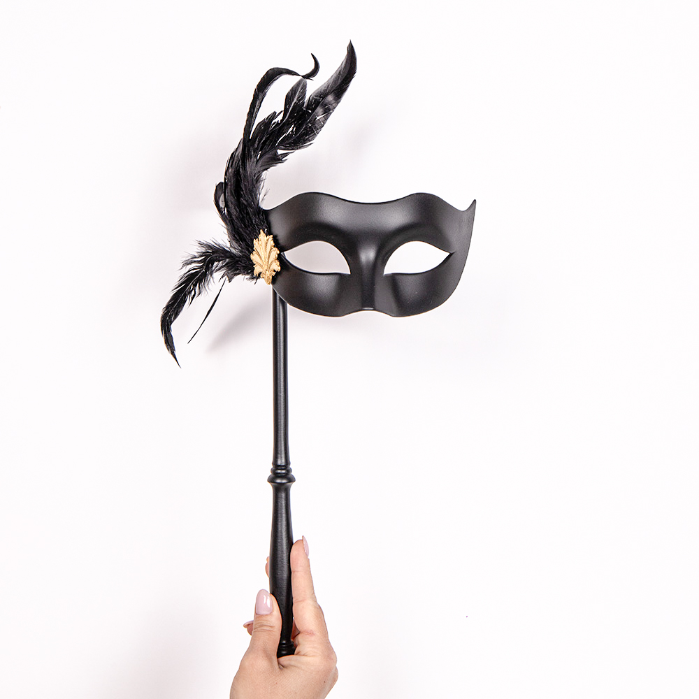 Eine elegante schwarze venezianische Maske mit einem Stab zum Halten, ausgestellt in einem Berliner Maskenladen.