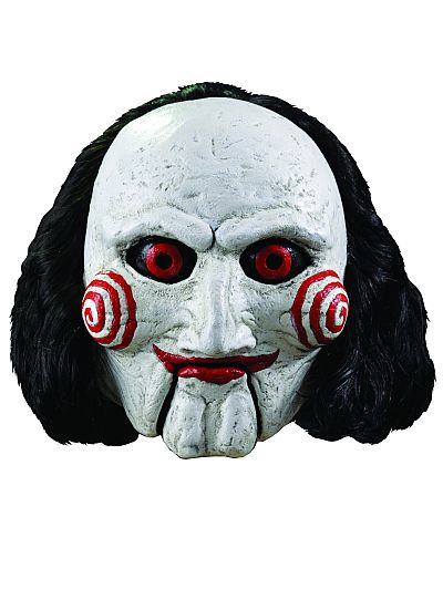 Eine Latexmaske der bekannten Puppe Billy aus den Saw-Filmen, mit weißem Gesicht, roten Spiralen auf den Wangen, roten Lippen und schwarzen Haaren.
