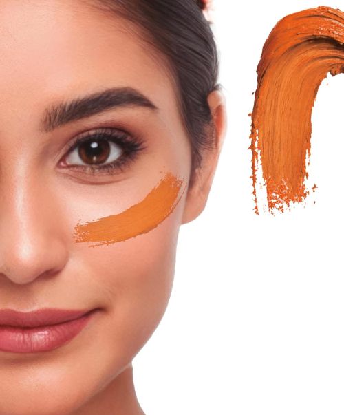Detaillierte Nahaufnahme eines Gesichts mit einem cremigen Klecks des Creme Make-ups in der Farbe orange als Farbmuster für Fasching oder Halloween.