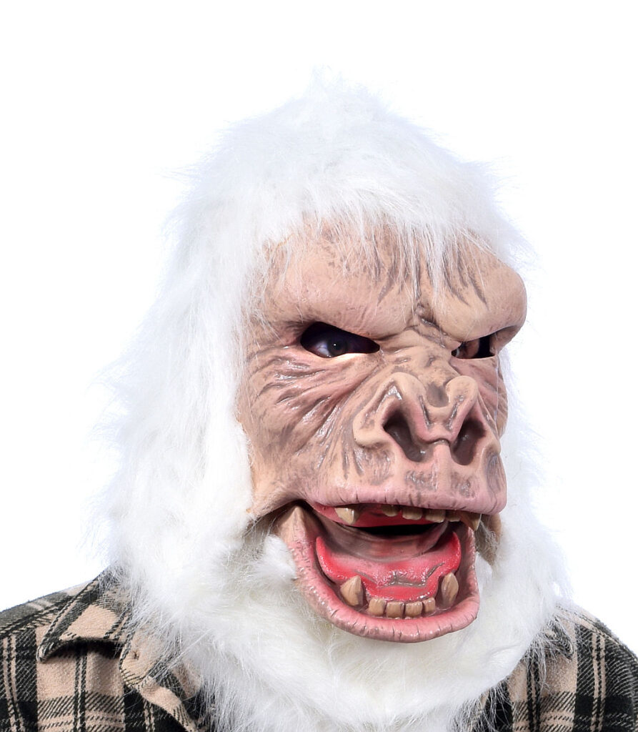 Eine weiße Yeti-Maske aus Latex mit zotteligen Fell-Details und grimmigen Gesichtszügen, die in den Verkaufsregalen eines Berliner Kostümladens präsentiert wird.